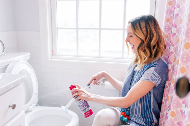 Smiling homeowner admiring a spotless bathroom with clean mirrors and grout, representing satisfaction with TropiClean’s professional cleaning services in South Florida.