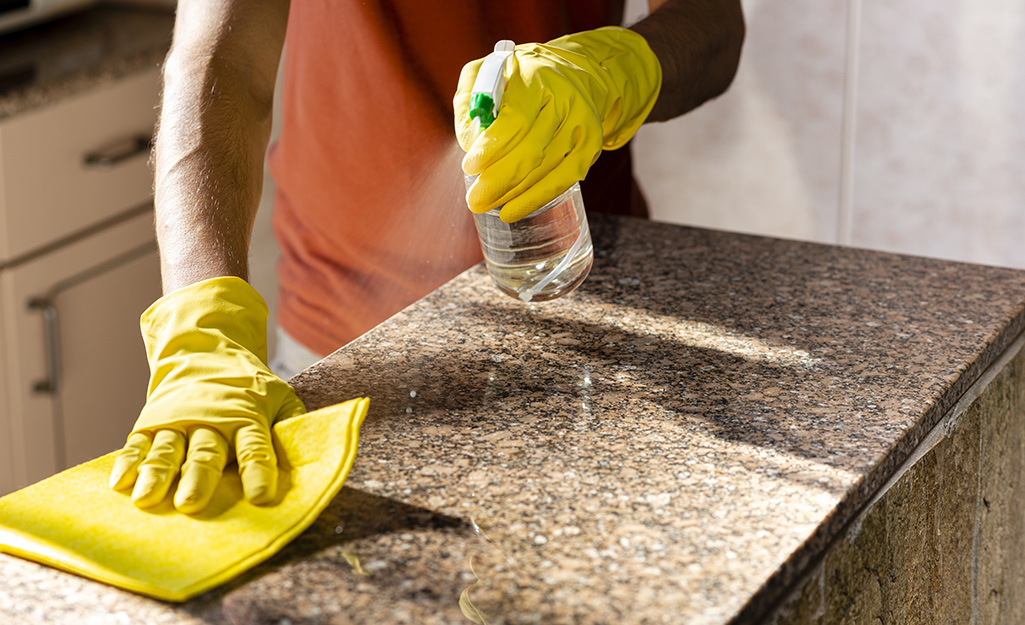 Disinfecting kitchen countertops with a natural cleaning solution of water and white vinegar in a well-lit South Florida kitchen.