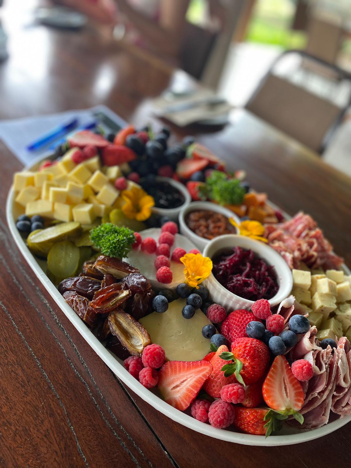 A grazing platter of cheeses, fruit, berries and cured meats on a timber table