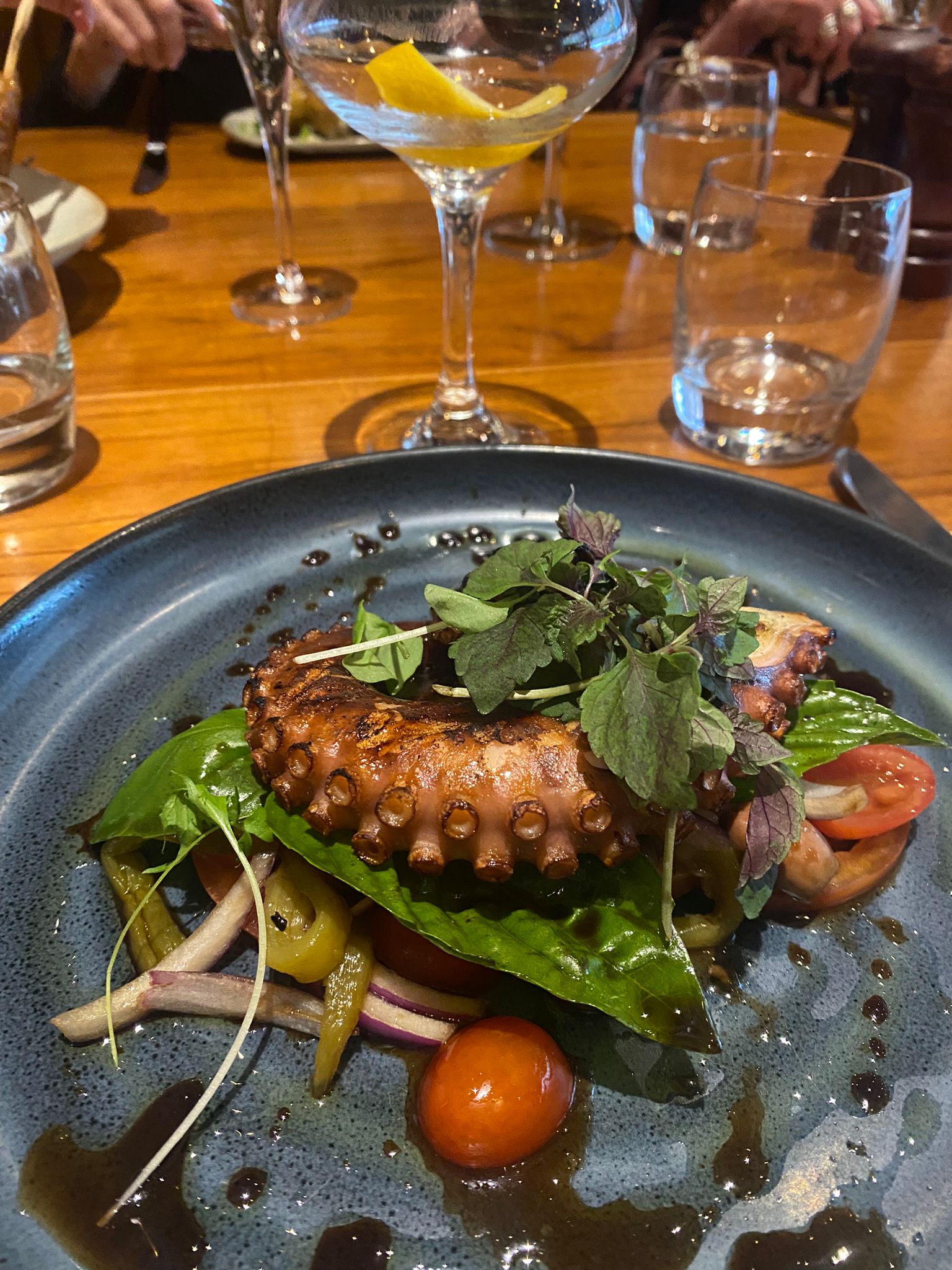 Chargrilled octopus with tomatoes and fresh greens at a restaurant lunch