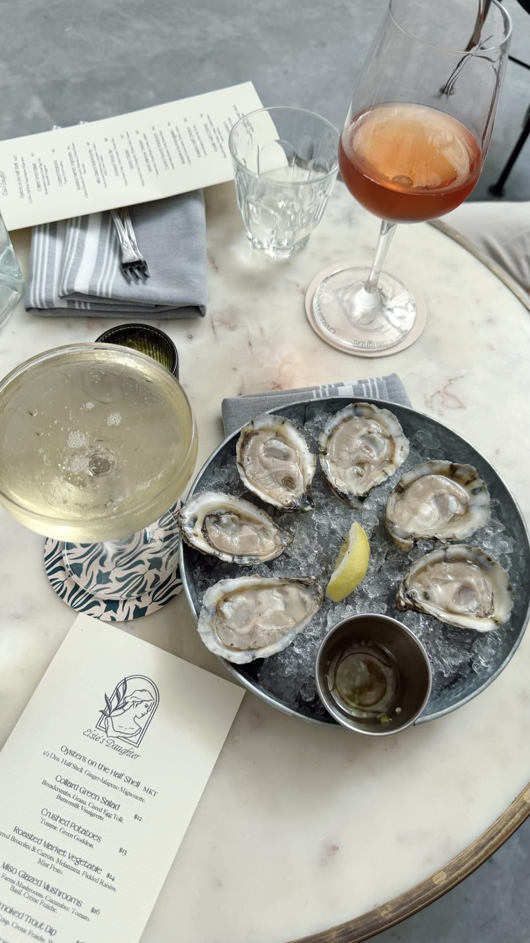 Freshly shucked oysters on ice with a glass of white wine and a rose