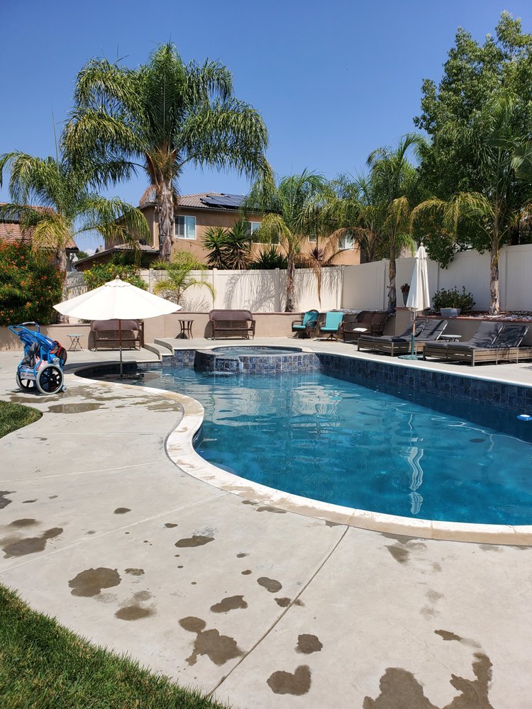 Pool service team cleaning a backyard pool in French Valley CA