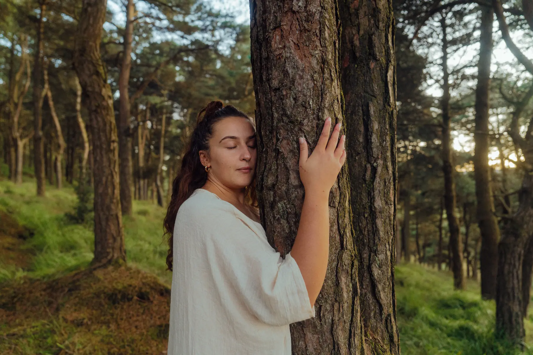 Woman resting against a tree at golden hour
