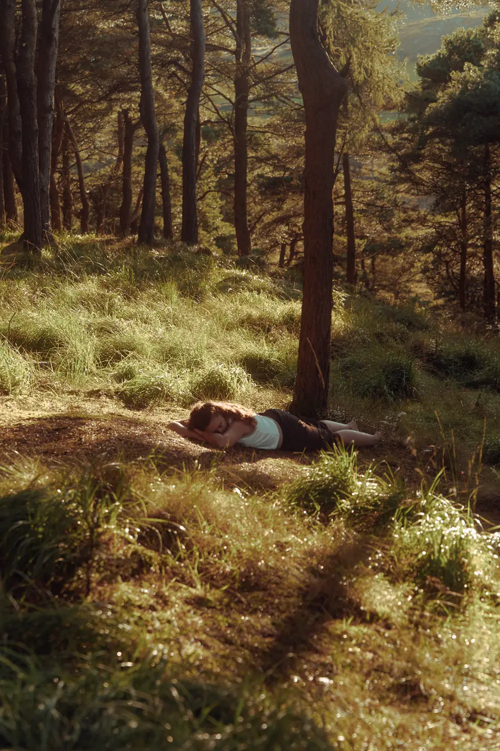 Woman resting on the forest floor in soft light