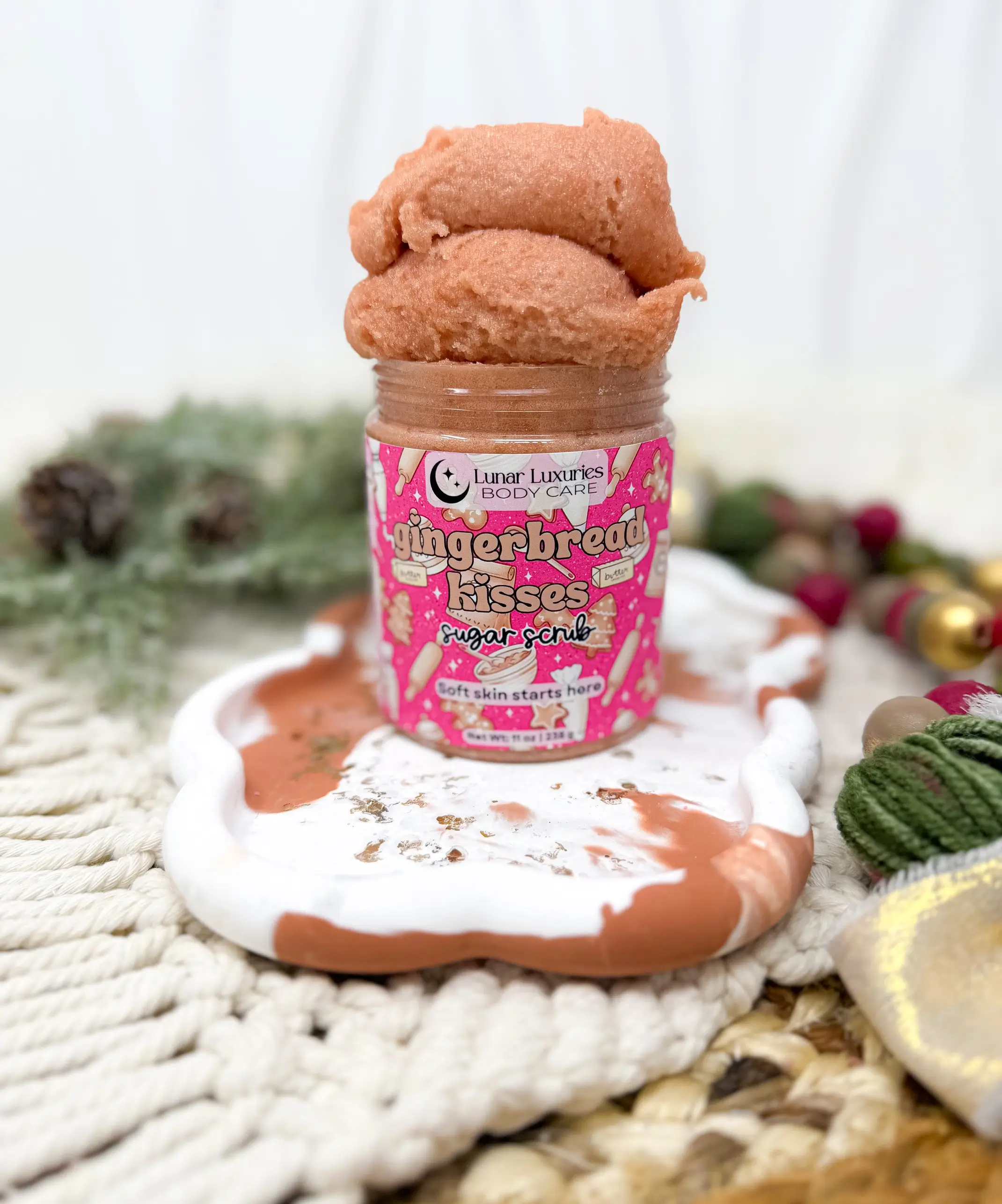 Lunar Luxuries Gingerbread Kisses Sugar Scrub in its original jar with a festive holiday backdrop.