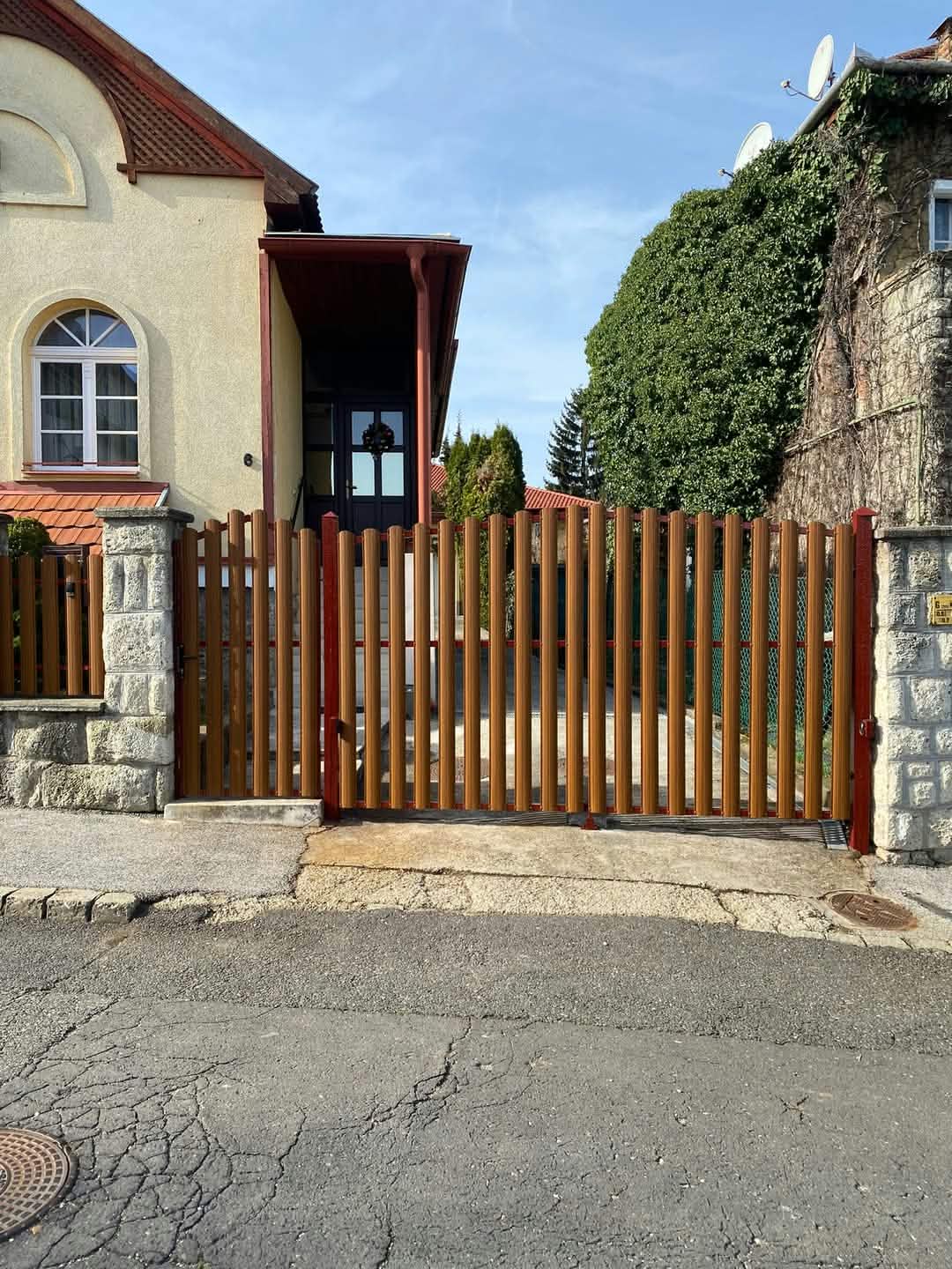 Barna függőleges pálcás fém kapu családi ház bejáratánál