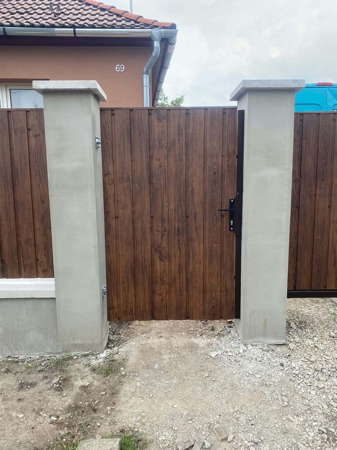 Zárt barna fém kiskapu és kerítés családi ház előtt