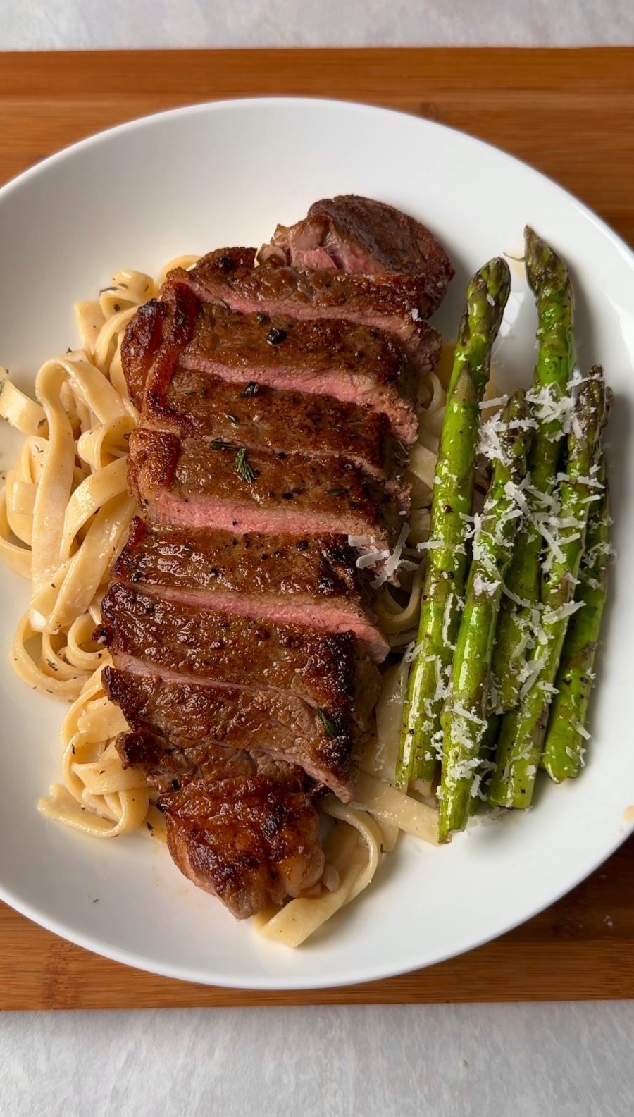 Steak Alfredo: steak en rebanadas sobre pasta Alfredo con espárragos