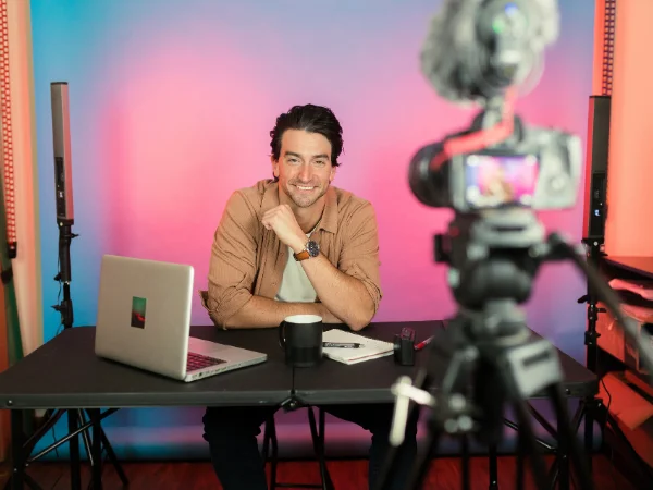 Content creator recording video in studio with camera and laptop, representing multimedia content creation to build trust and authority.
