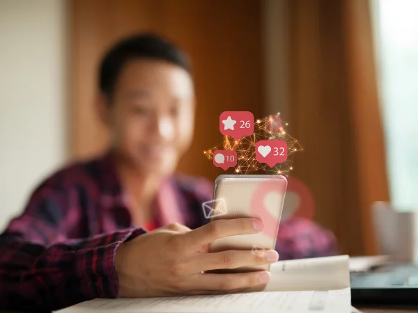 Person holding smartphone with floating social media icons, symbolising reviews, testimonials, and social proof that build trust for AI visibility.