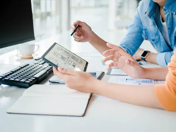 Two colleagues reviewing digital content strategy on tablet at office desk, showing importance of updating content for SEO and AI search.