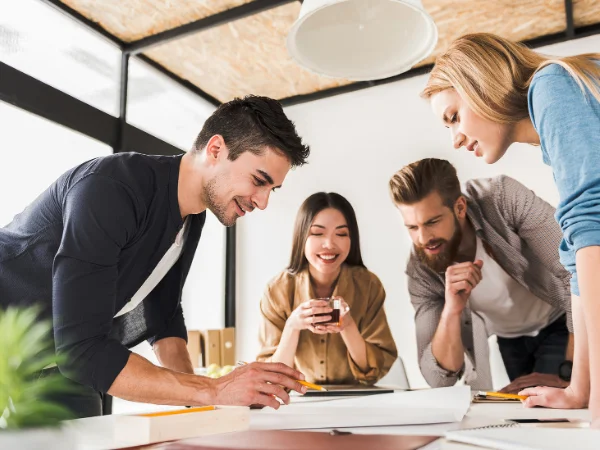Team of four colleagues collaborating around a table, illustrating collaboration and case study content to demonstrate expertise.