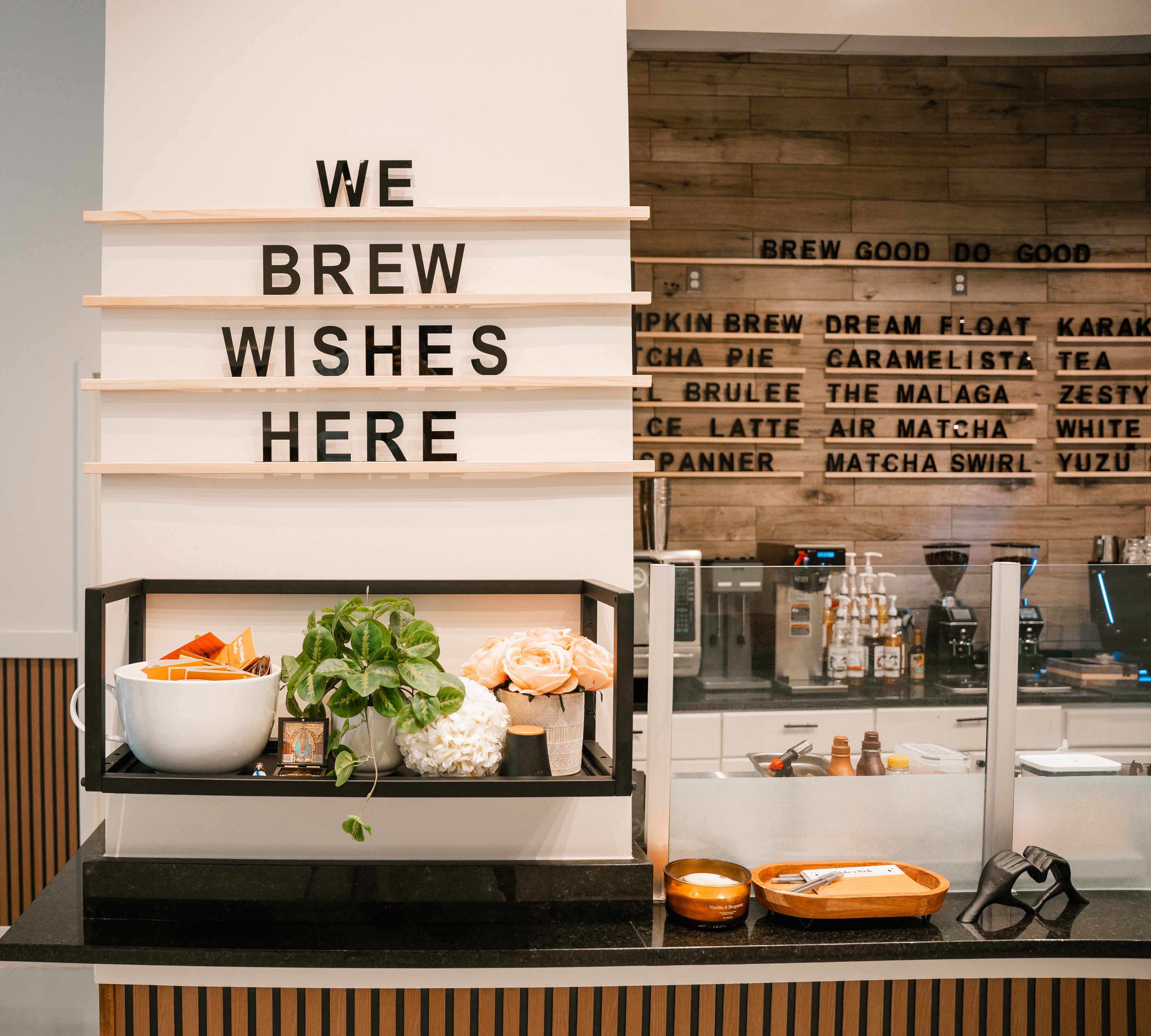 WE BREW WISHES HERE sign with plants