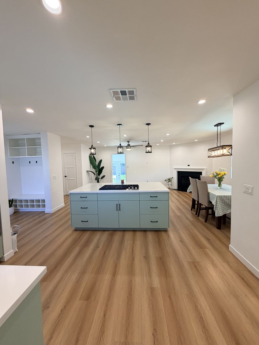 Open floor plan with a sage green kitchen island, pendant lights and wood-look flooring