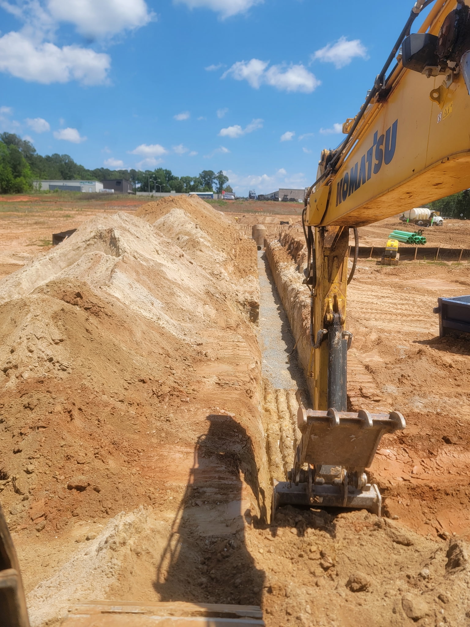 Excavator preparing a drainage trench with stone bedding