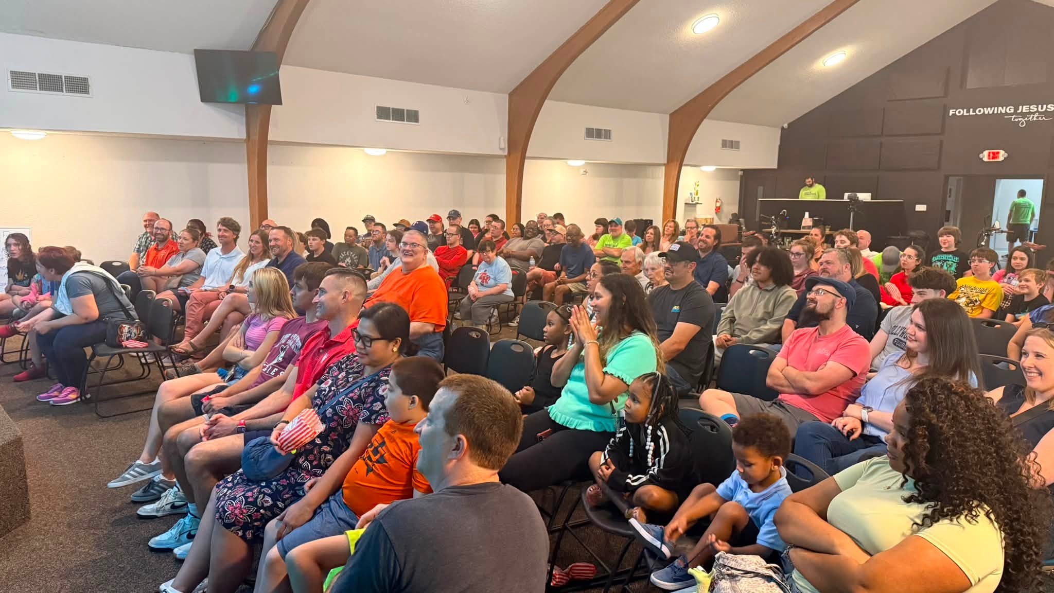 A packed church auditorium of families laughing during a ZingerZ clean comedy fundraiser