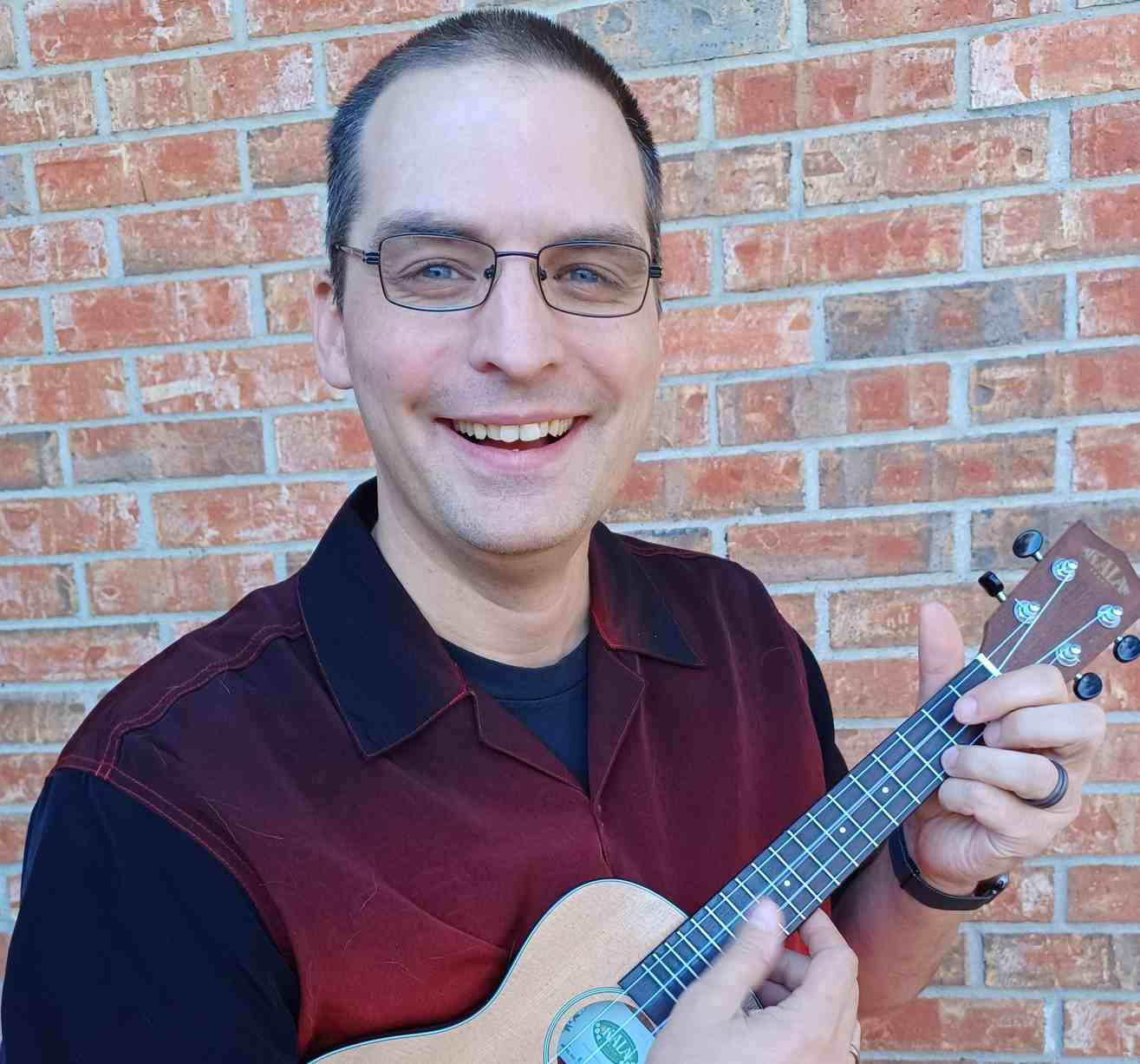 ZingerZ host and emcee smiling with a ukulele