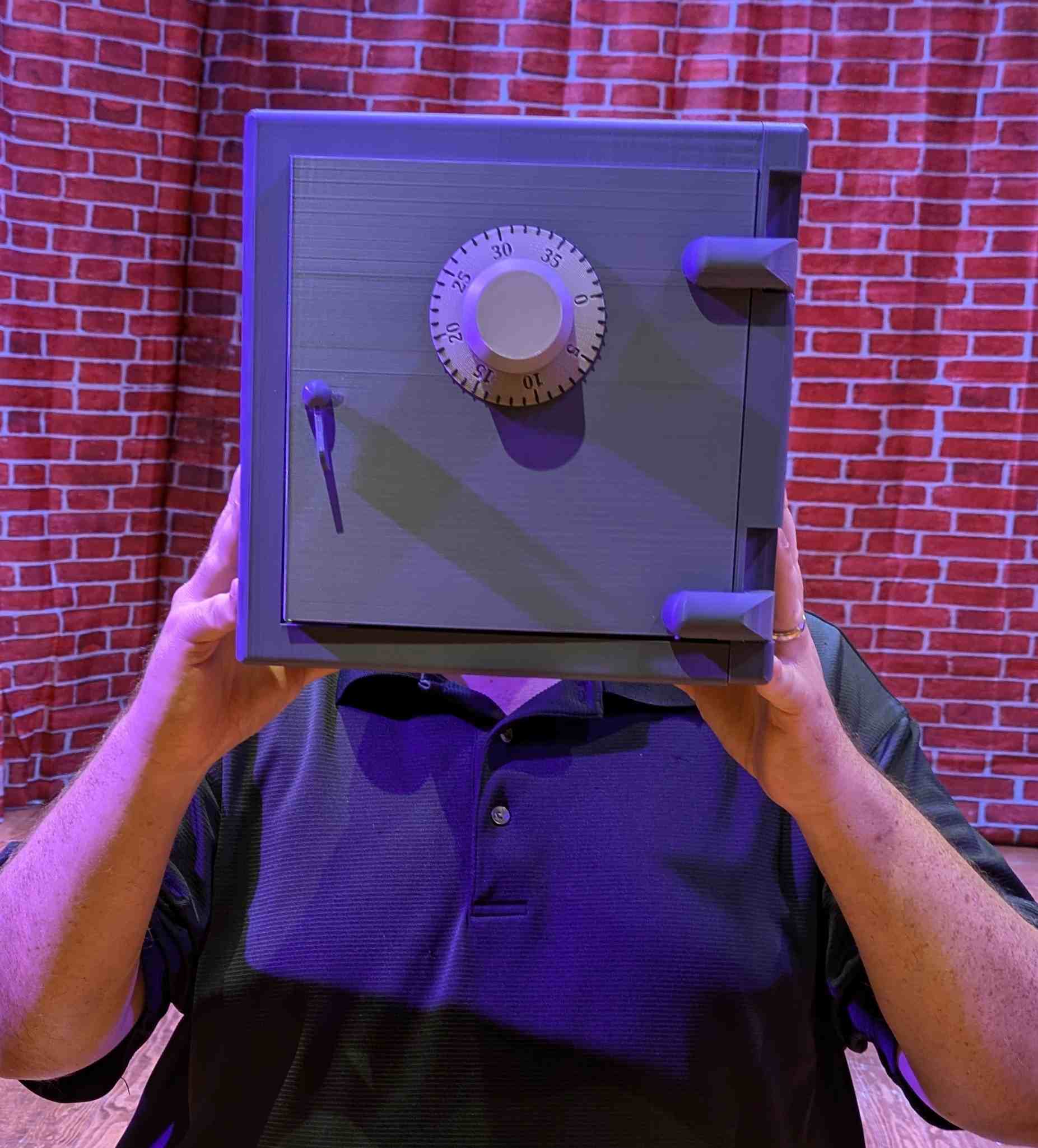 Fundraising coach holding a prop safe in front of his face onstage