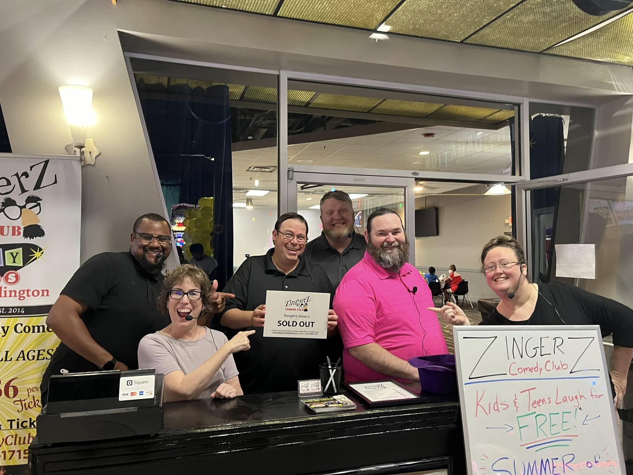 ZingerZ cast at the check-in table with a sold-out sign before the show
