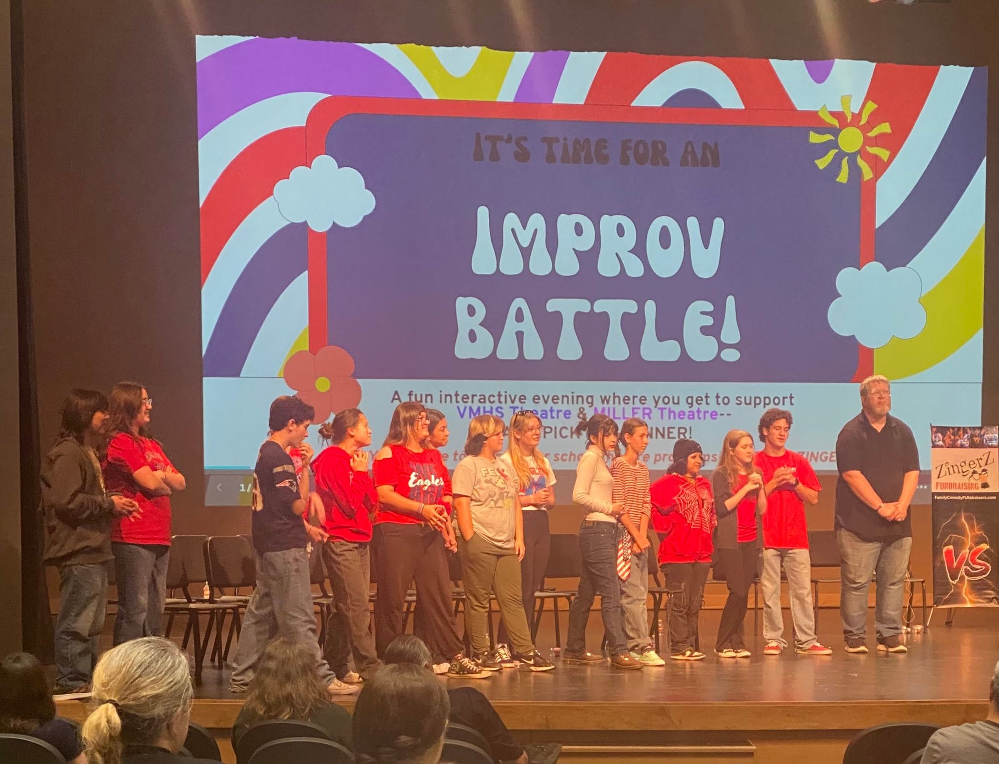 Two student teams lined up onstage under an Improv Battle screen