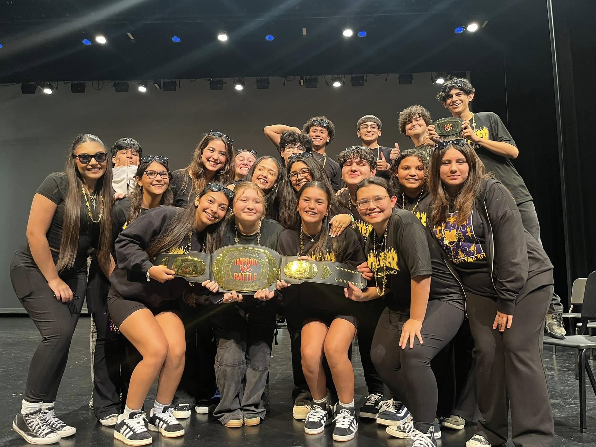 Student team celebrating with the Improv Battle championship belt