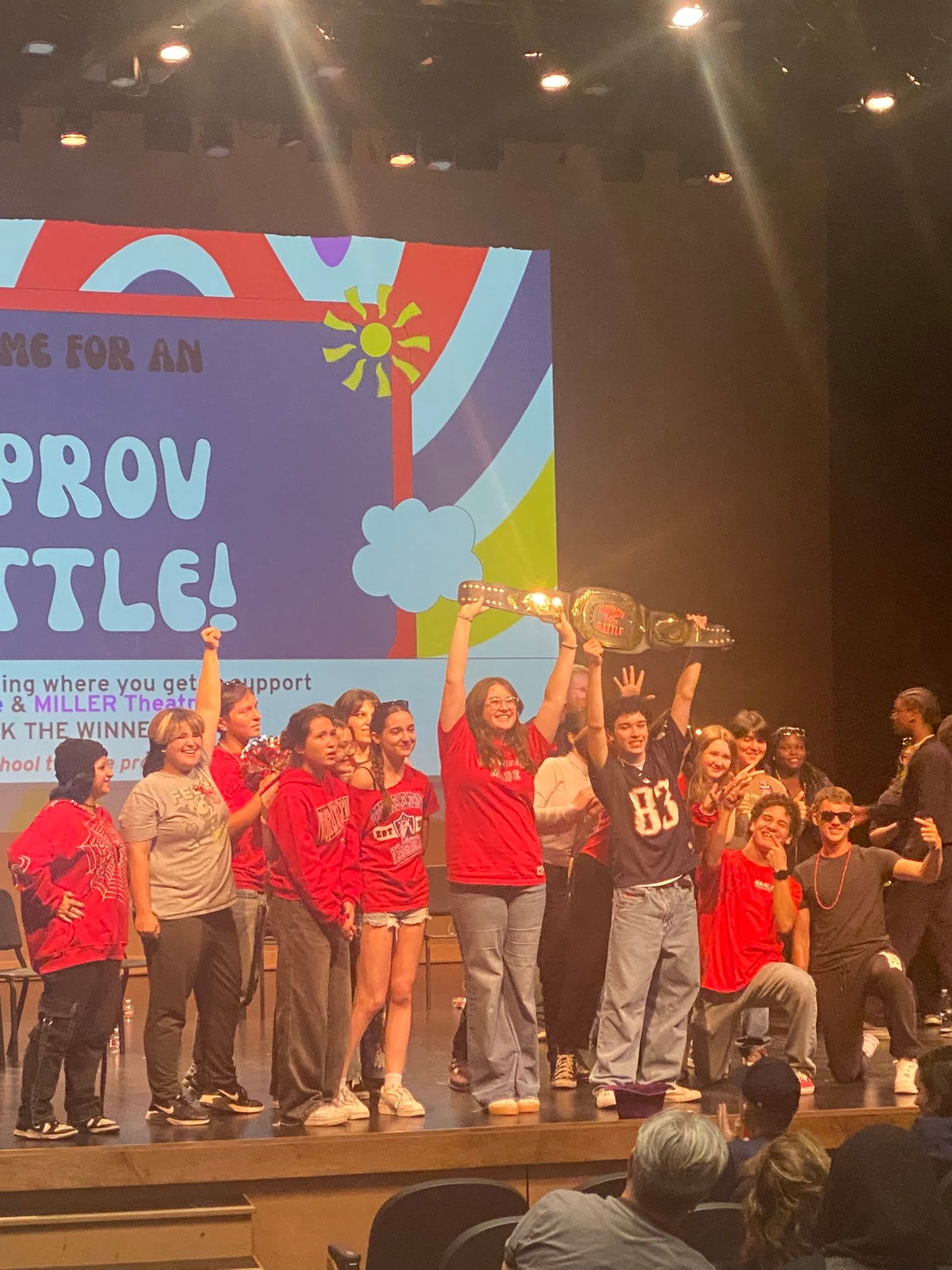 Improv Battle winners raising the championship belt on stage