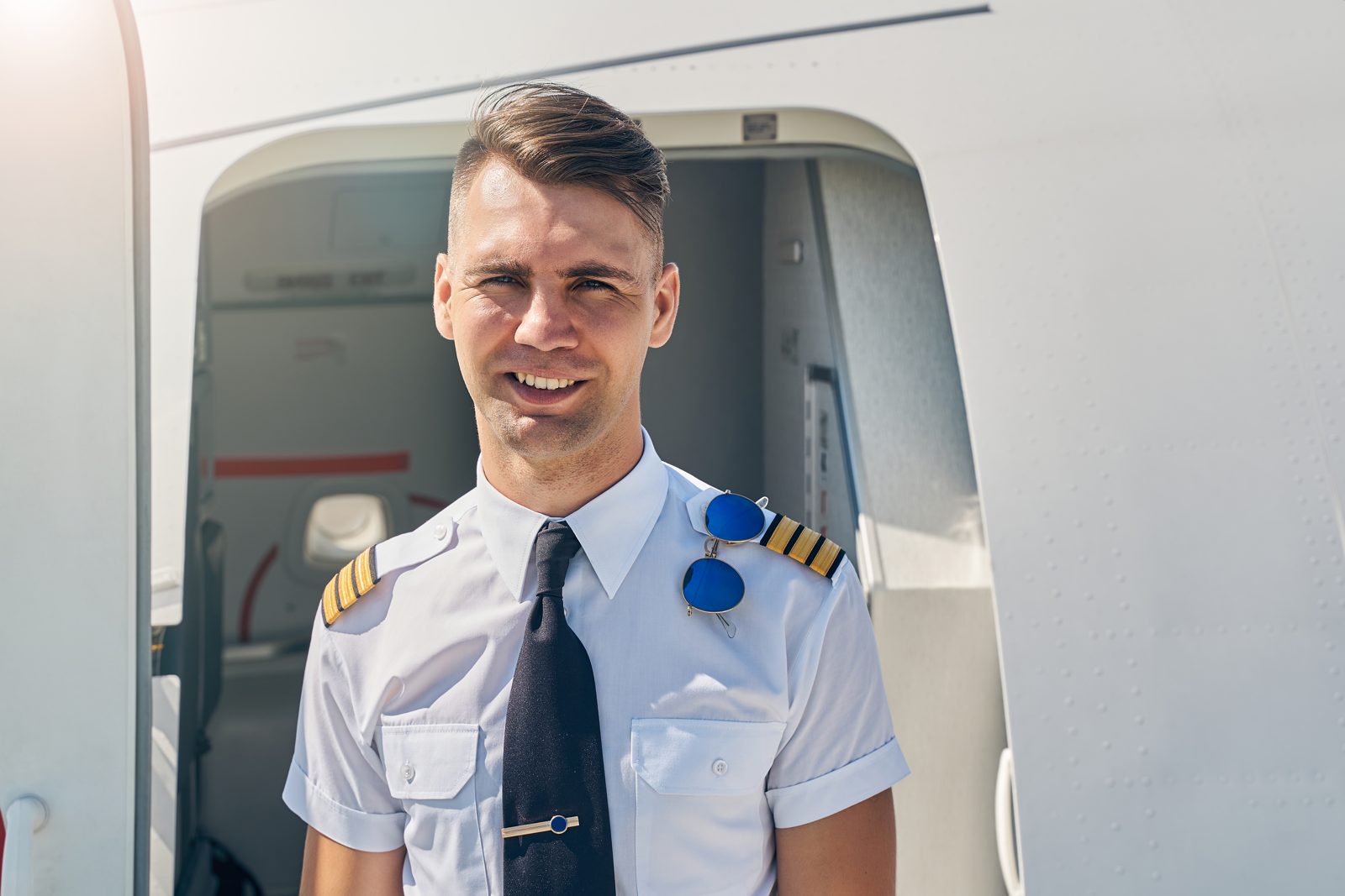 A first officer in uniform standing at the aircraft door