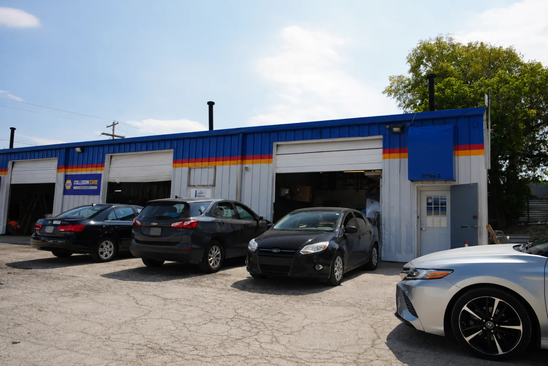 Exterior of the Excite Collision Repair shop in Westerville with open repair bays and vehicles in for service