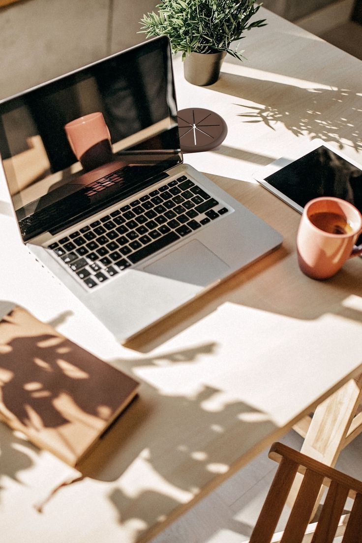 Espace de bureau esthétique avec un ordinateur et tasse café sous un rayon de soleil