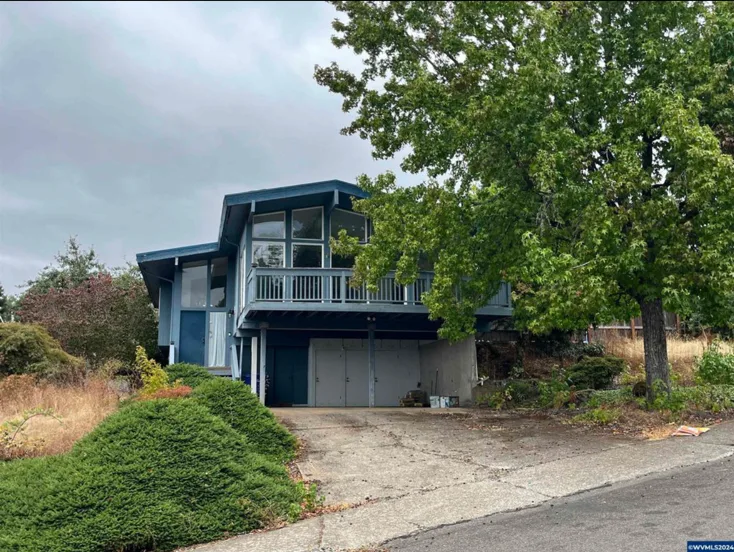 Before photo — West Salem split level home with outdated exterior, worn deck, and aging siding before renovation