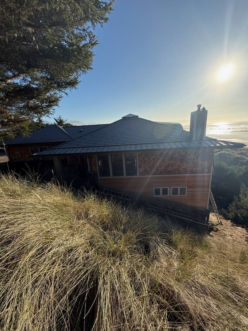 Cannon Beach home after exterior renovation seen from driveway angle with new cedar siding and synthetic slate roof