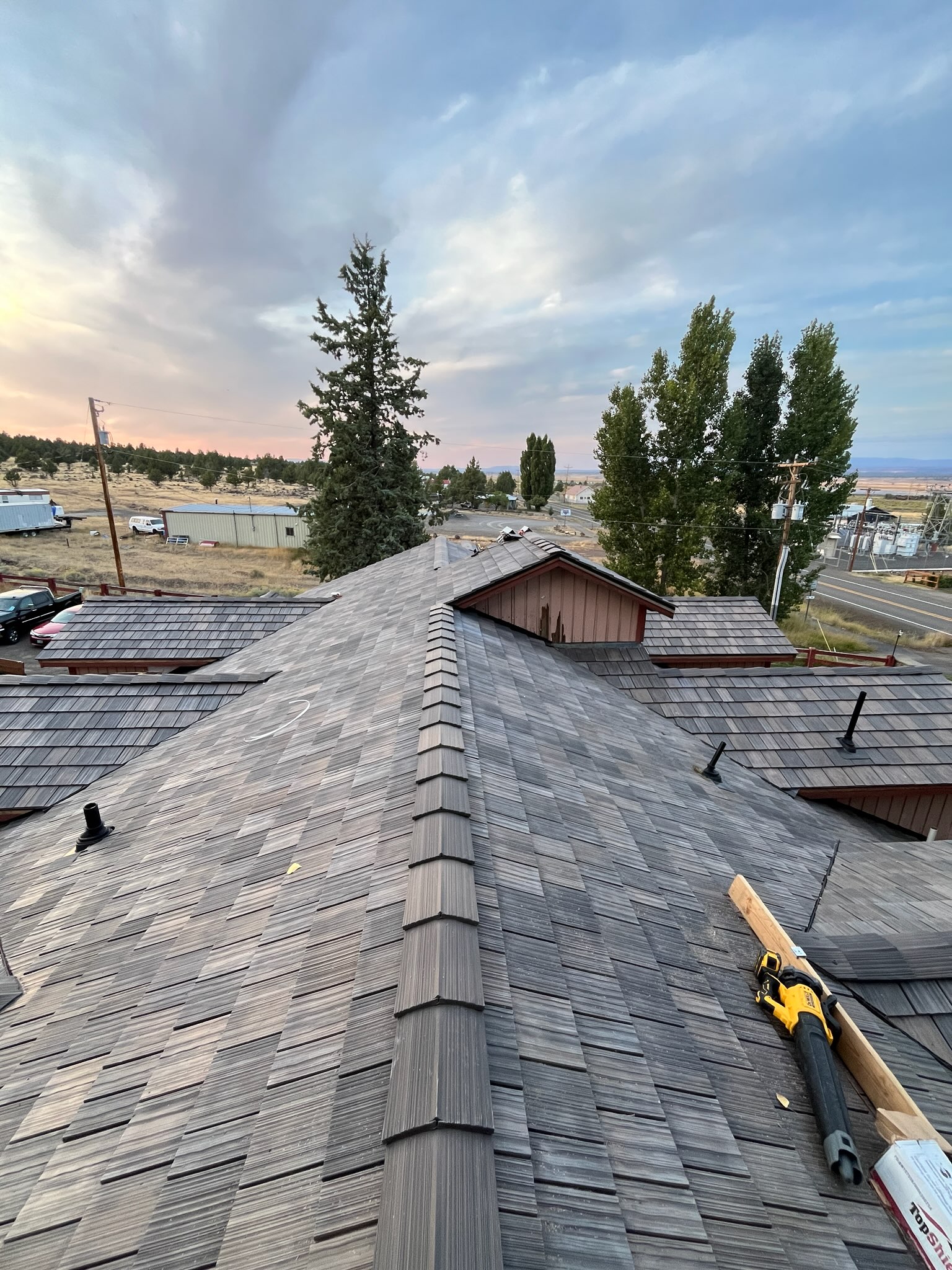 Synthetic slate roof installation in progress with hip detailing and ridge venting on Oregon Coast home