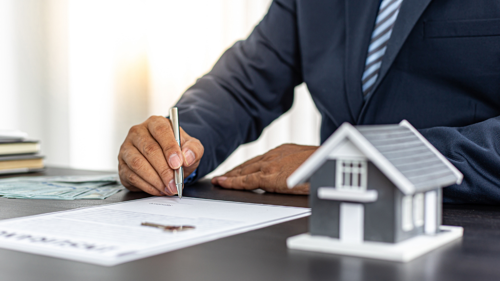 A close-up of a real estate professional signing property documents with a miniature house displayed in the foreground. The image represents property acquisitions, investment decisions, contract execution, and financial planning in real estate. It supports topics such as multifamily investing, commercial real estate, property transactions, investment strategy, due diligence, market analysis, and how urban migration trends are affecting Albany real estate. A close-up of a real estate professional signing property documents with a miniature house displayed in the foreground. The image represents property acquisitions, investment decisions, contract execution, and financial planning in real estate. It supports topics such as multifamily investing, commercial real estate, property transactions, investment strategy, due diligence, market analysis, and how urban migration trends are affecting Albany real estate.
