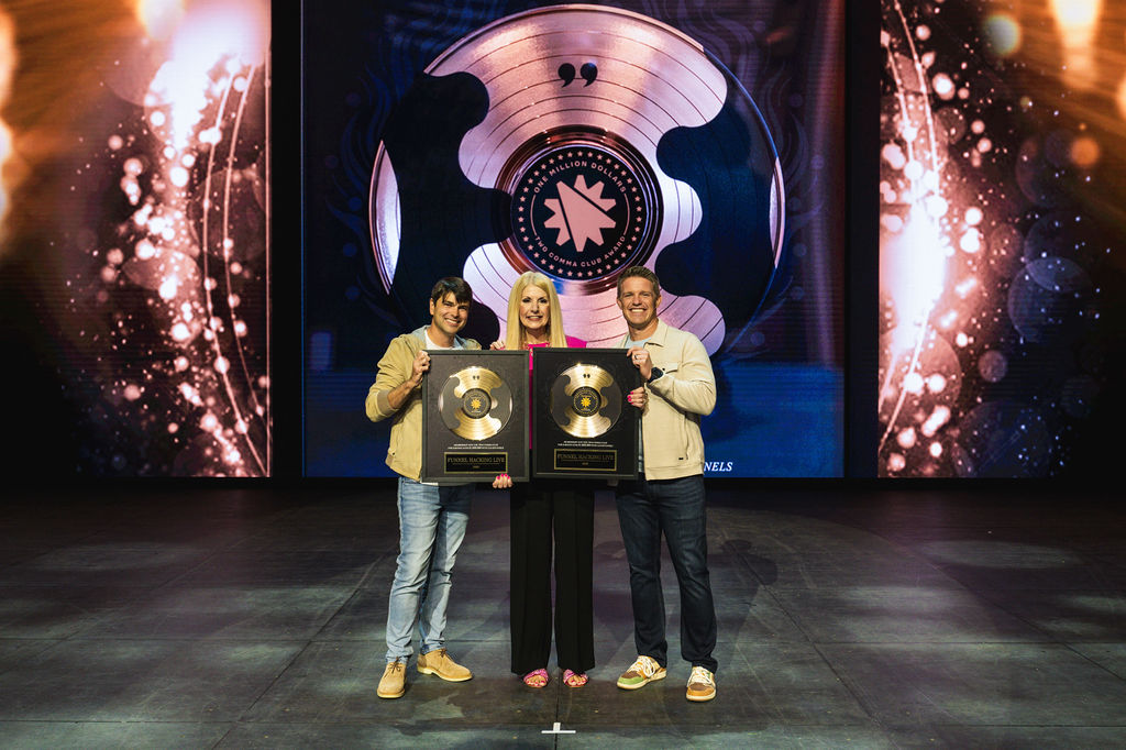 Christina Rowe on stage at Funnel Hacking Live holding Two Comma Club Award plaques