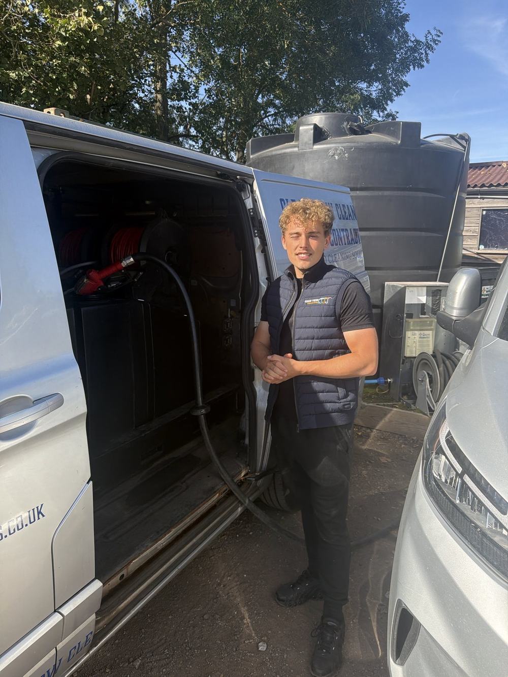 A van tank filling with purified water from an automatic nozzle while Dylan stands back