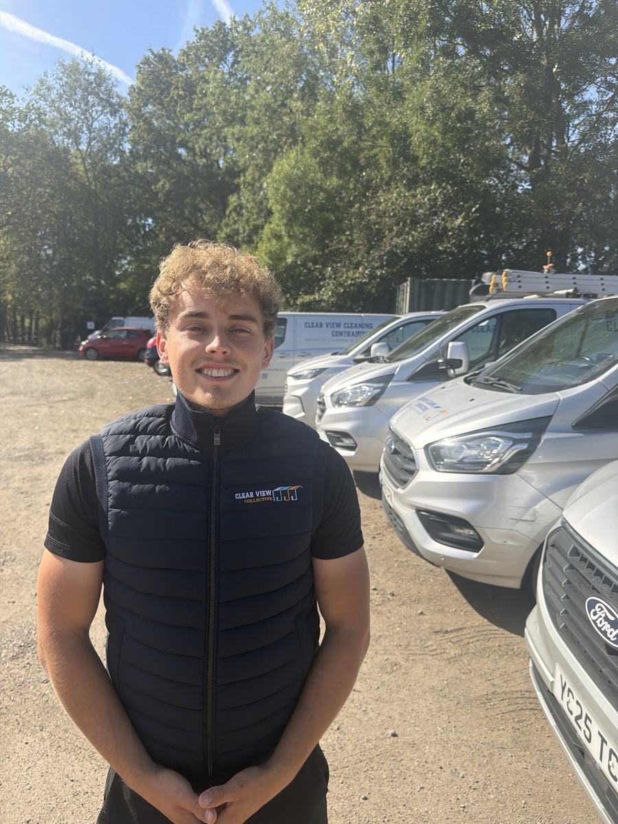 Dylan from Clear View, smiling, with the vans behind him