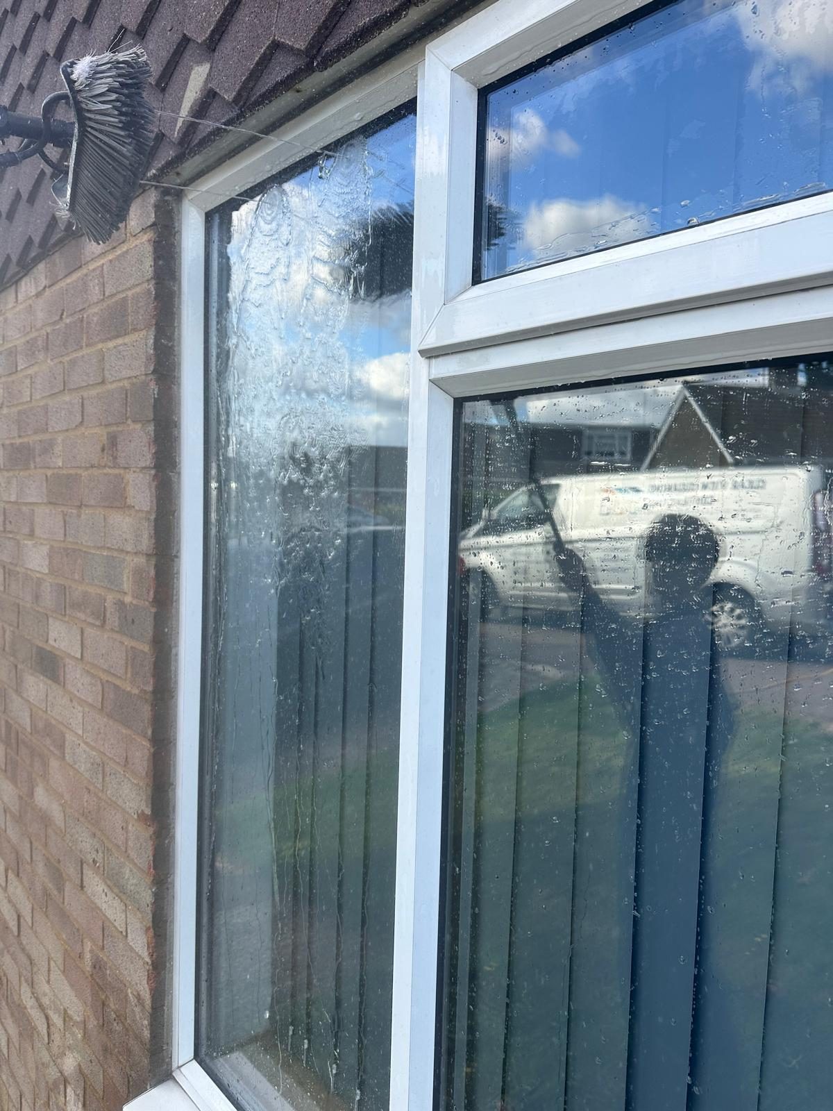 Purified water running down a freshly rinsed window, with a Clear View van reflected in the glass