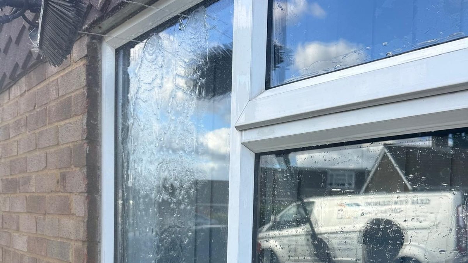 Purified water running down a freshly rinsed window, with a Clear View van reflected in the glass