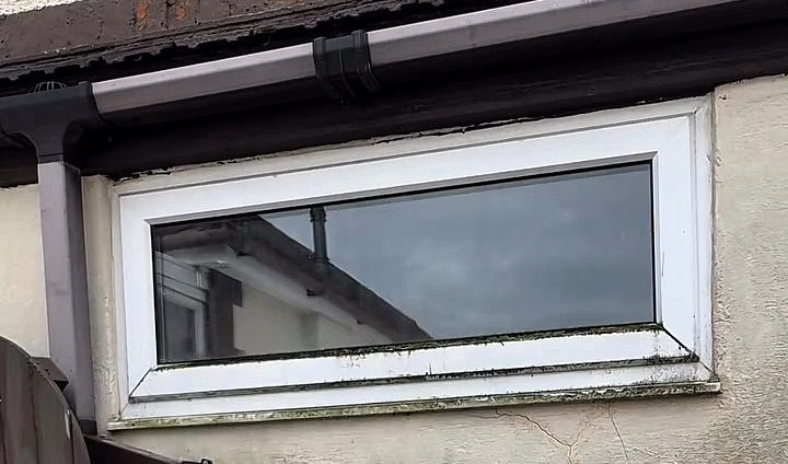 A water-fed pole brush rinsing a window with purified water until the glass is clear