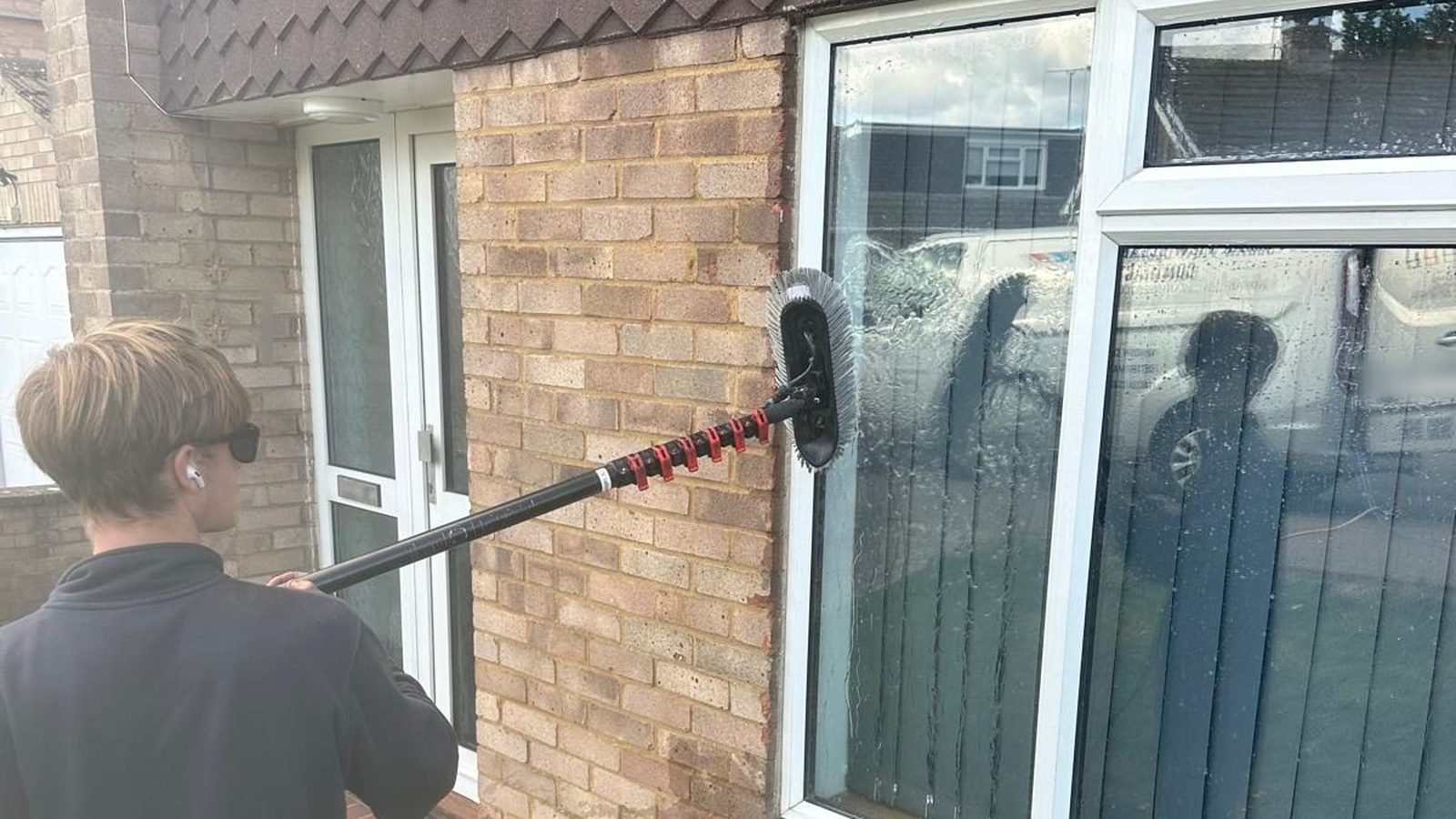 A Clear View team member using a water-fed pole on a ground-floor window