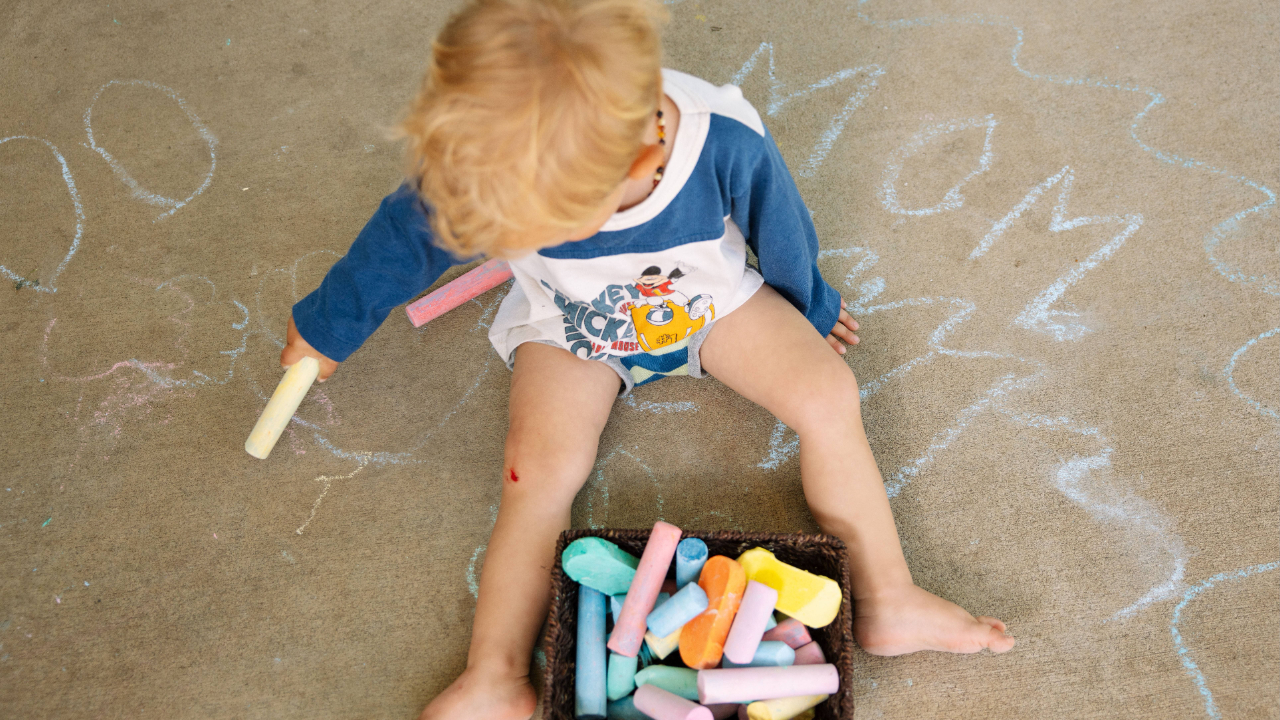 Young kid creating patterns using colored sidewalk chalk