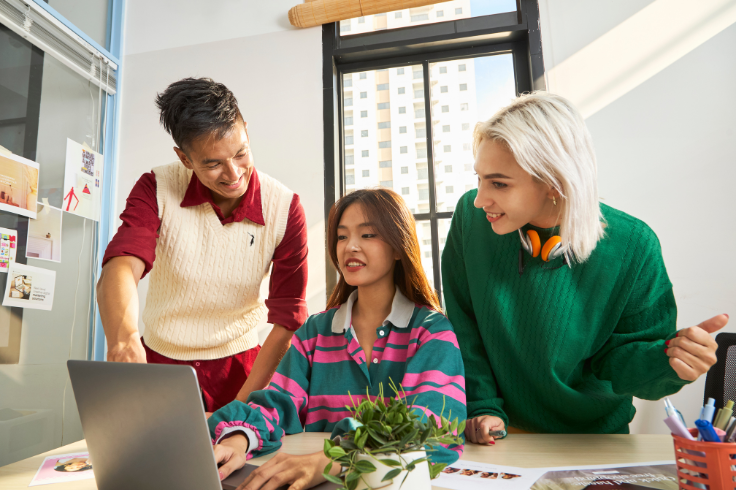 three brand experts conversing around a laptop