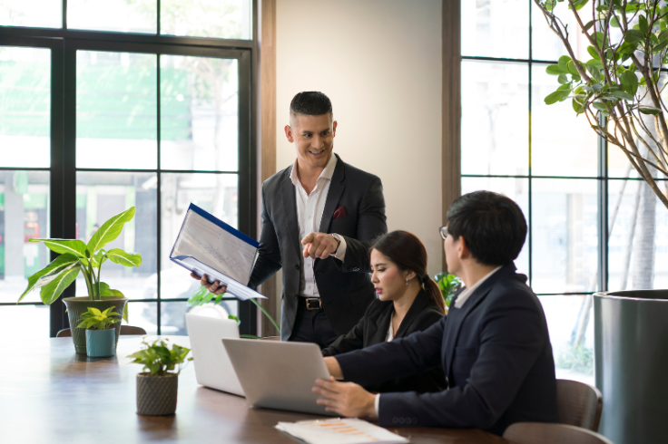 Man holding sales graph talks to two other people