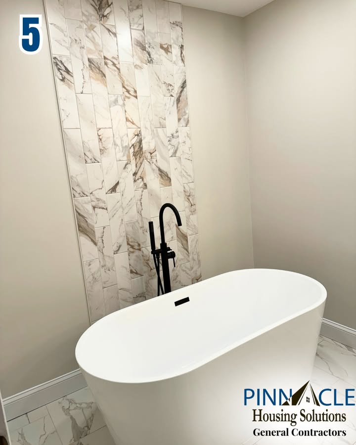 Oval soaking tub with a black floor-mounted faucet and a vertical strip of marble-look tile in a Chester County, PA bathroom remodel.