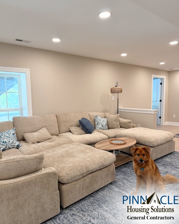 Open seating area in a finished Chester County, PA basement with a large sectional sofa, recessed lighting, and a half wall in the background.