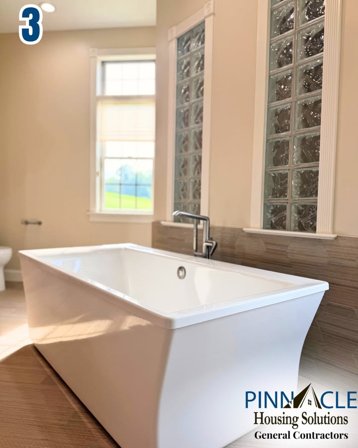 Rectangular freestanding soaking tub with a chrome faucet beside tall glass block windows in a Chester County, PA bathroom remodel.
