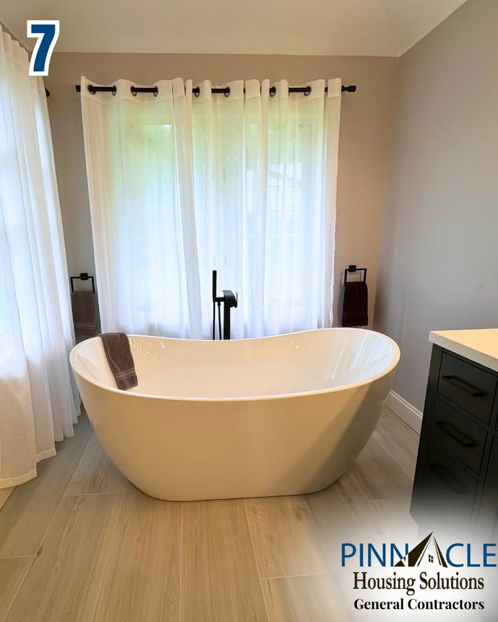 Soaking tub in front of a window with sheer curtains, next to a dark vanity, in a Chester County, PA bathroom remodel.