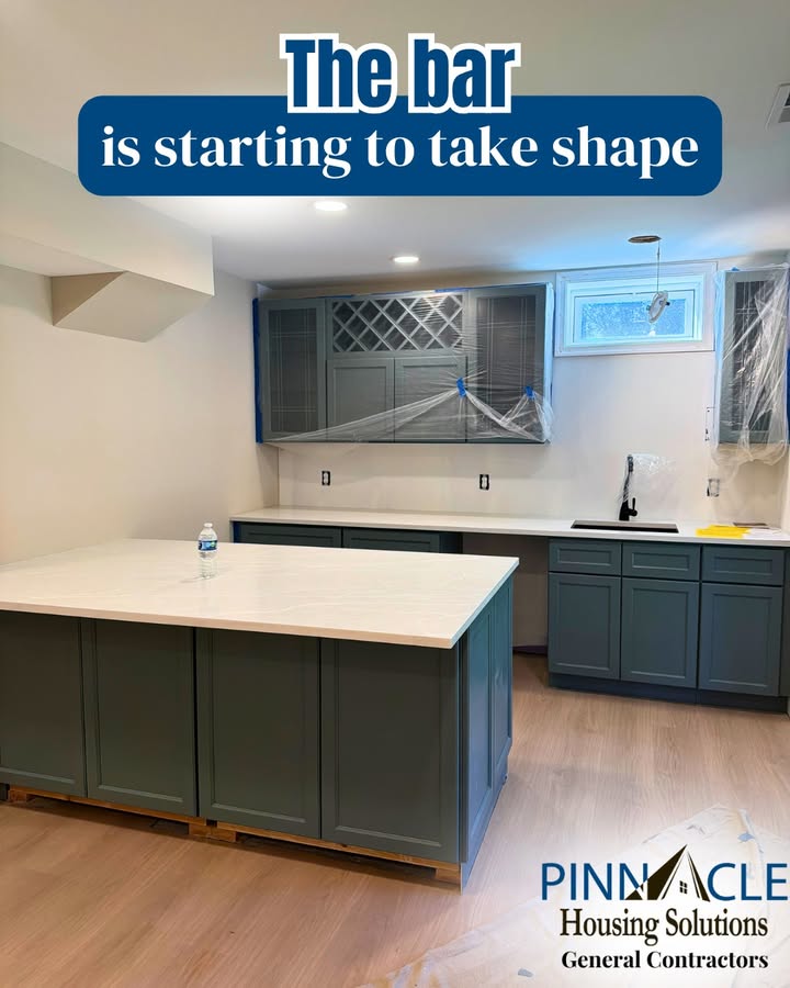 Gray-green bar cabinets and a peninsula with a white countertop going in during a Chester County, PA basement remodel.