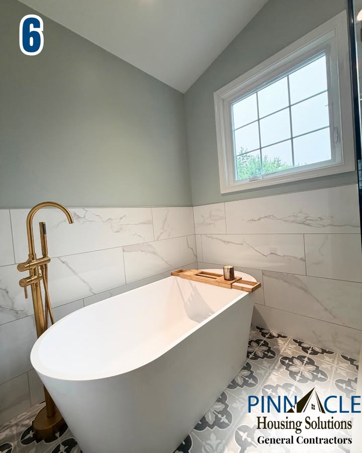 Soaking tub with a brass floor-mounted faucet, marble-look wall tile and a patterned tile floor in a Chester County, PA bathroom remodel.