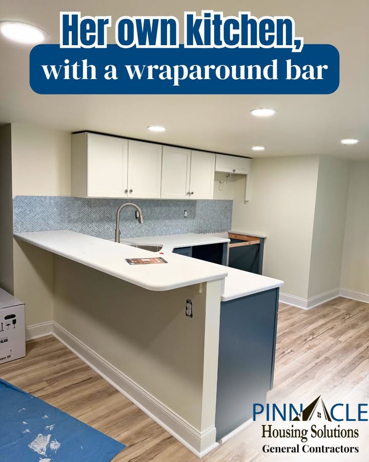 Basement suite kitchen with a wraparound bar, white shaker upper cabinets, a herringbone tile backsplash and wood-look flooring.